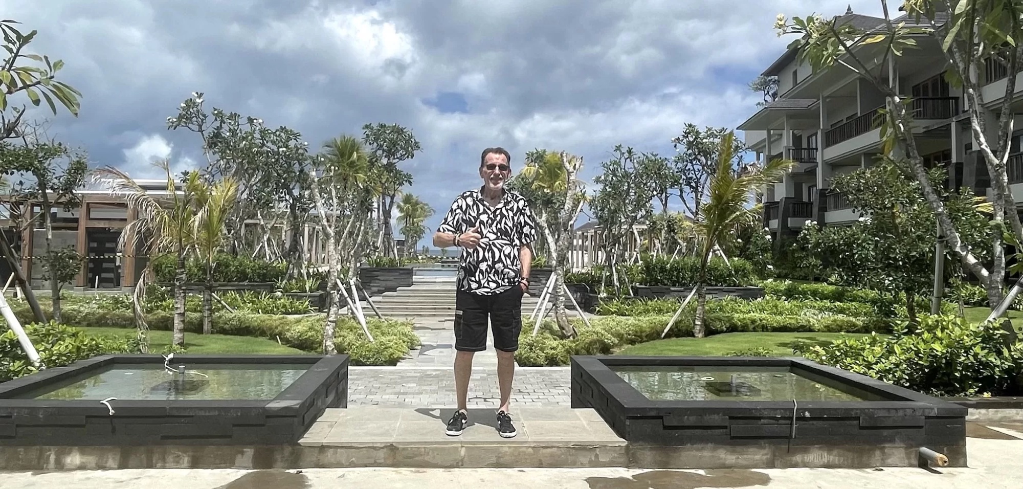 Bert standing among resort gardens and buildings in Bali